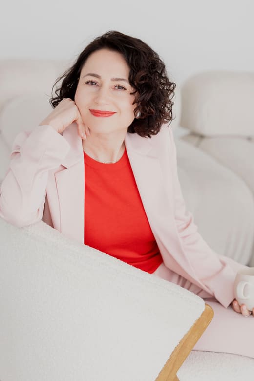 Herzschätzerin, Claudia di Chio sitzend und angelehnt mit einem Ellenbogen auf dem Tisch, in der linken Hand eine Tasse haltend.