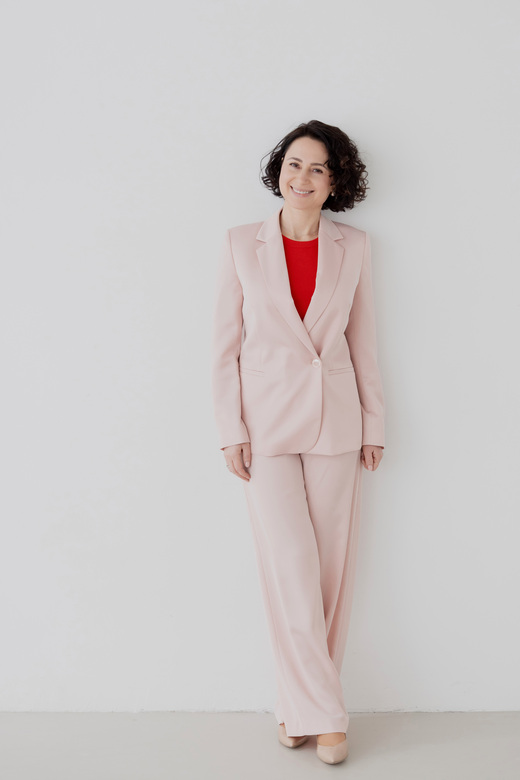 Herzschätzerin, Claudia Di Chio, im rosa Blazer, angelehnt an die Wand