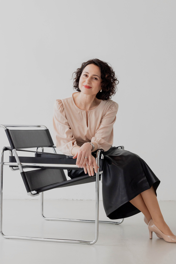 Herzschätzerin, Claudia di Chio sitzend auf einem schwarzen Lederstuhl